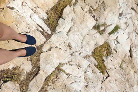 Unrecognizable personn wearing espadrilles and standing on a rock. Top view.の写真素材