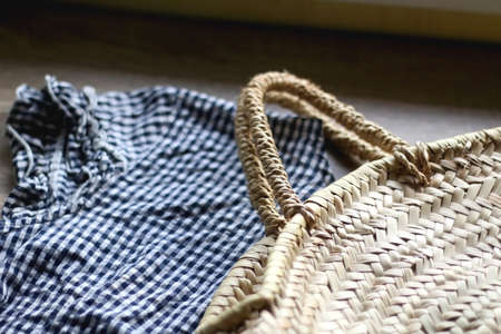 Straw bag and gingham prrint top. Summer outfit details. Selective focus.の写真素材