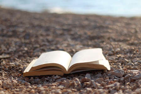 Open book on a beach at sunset. Selective focus.の写真素材