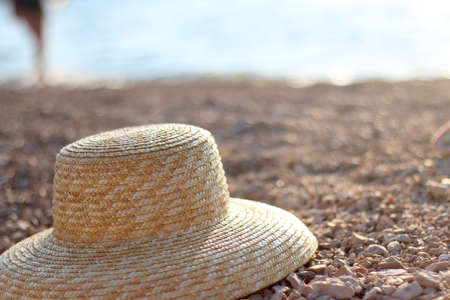 Straw hat on a beach at sunset. Selective focus.の写真素材