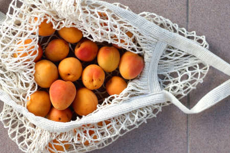 Reusable mesh bag filled with apricots. Top view.の写真素材