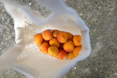 Reusable mesh bag filled with apricots. Top view, selective focus.の写真素材