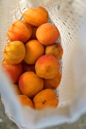 Reusable mesh bag filled with apricots. Top view, selective focus.の写真素材