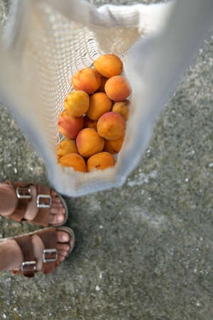 Unrecognizable person holding a bag of apricots. Top view, selective focus.の写真素材