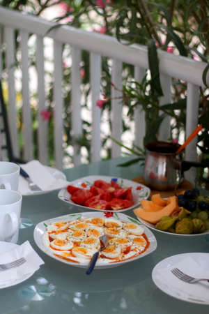 Boiled eggs with yoghurt sauce, tomato salda and various fruit on the breakfast table. Selective...