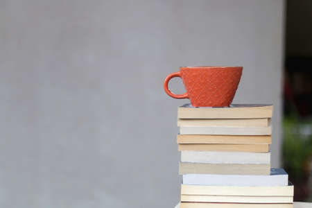 Stack of paperback books and a cup of coffee or tea. Selective focus.の写真素材