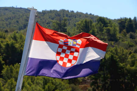 Flag of Croatia blowing in the wind. Forest in the background. Selective focus.