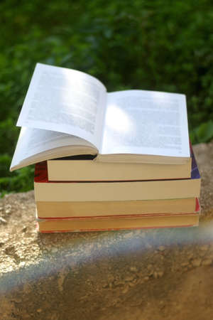 Stack of books in the garden. Selective focus, lens flare.