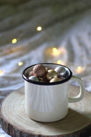 Mug filled with golden Christmas ornaments. Selective focus, bokeh lights.の写真素材