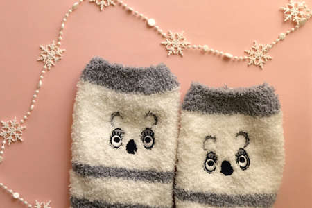 Cute fuzzy socks and snowflake garland. Flat lay, pink background.