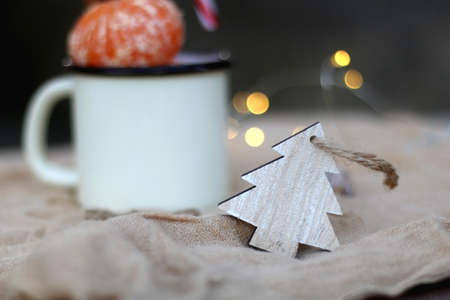 Christma stree ornament and mug filled with tangerines and candy cane. Selective focus, bokeh...