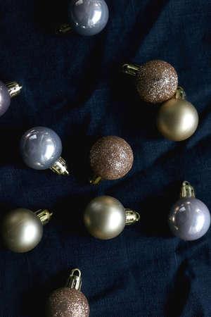 Christmas baubles in gold tones on dark blue background. Flat lay.