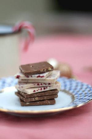 Stack of chocolate pieces, Christmas deoc rin the background. Selective focus.