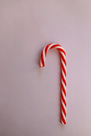 Candy cane on pastel pink background. Top view.