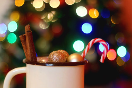 Enamel mug filled with Christmas decorations, in front of the Christmas tree. Selective focus.の写真素材