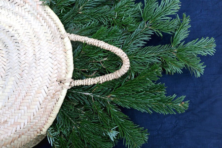 Wicker basket filled with fresh pine tree branches. Top view, dark blue background.の写真素材