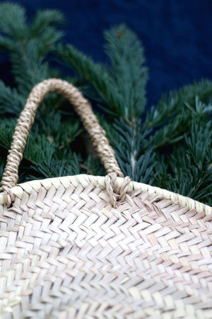 Wicker basket filled with fresh pine tree branches. Selective focus, dark blue background.の写真素材