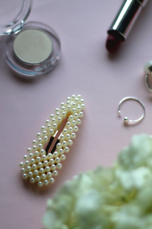 Silver rings, pearl barrette, various make up and flowers. Pastel background, selective focus.の写真素材