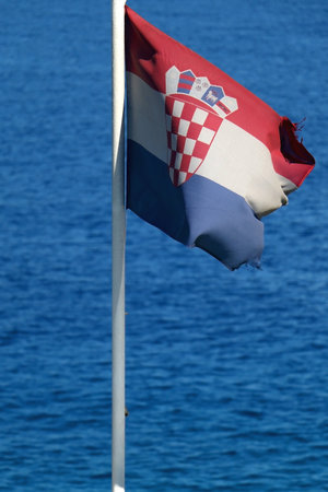 Flag of Croatia, blowing in the wind. Adriatic sea in the background. Selective focus.の写真素材