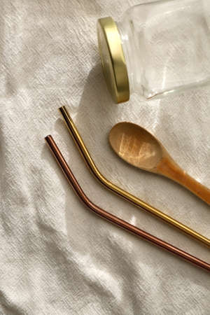 Sustainable kitchen utensils on linen cloth: mason jar, wooden spoon and metal straws. Top view.の写真素材
