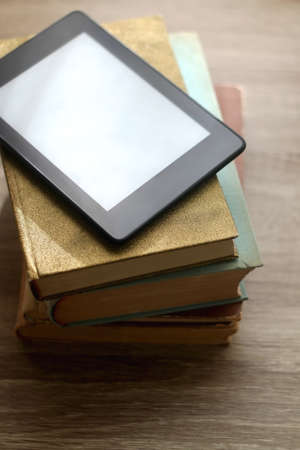 Stack of vintage books and e-book reader on top. Selective focus.