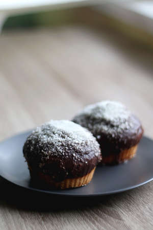 Two large homemade muffins with chocolate and coconut topping. Selective focus.