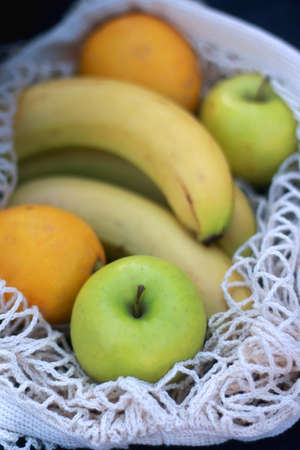 Crochet bag filled with bananas, apples and lemons. Selective focus.の写真素材
