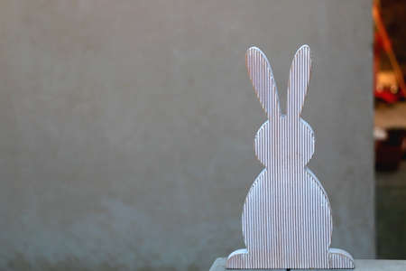 Wooden bunny and concrete wall, minimal Easter decoration. Selective focus, copy space.の写真素材
