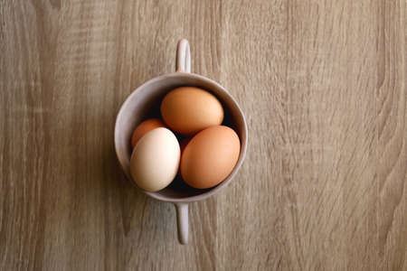 Ceramic bowl filled with fresh free range eggs on wooden table. Flat lay.の写真素材