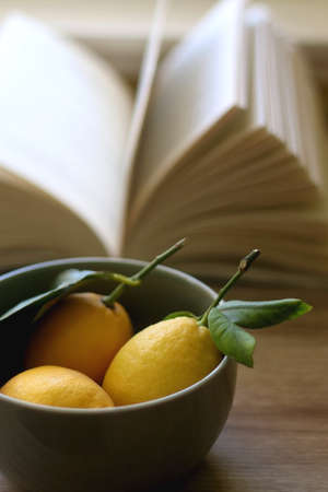Bowl of lemons and open book on a table. Selective focus.の写真素材