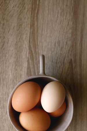 Ceramic bowl filled with fresh free range eggs on wooden table. Flat lay.の写真素材
