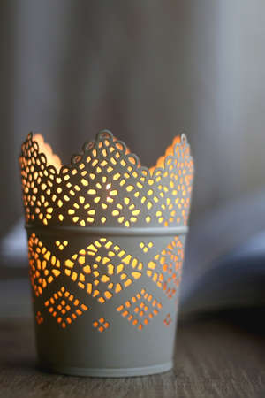 Open book and lit candle on a table. Selective focus.