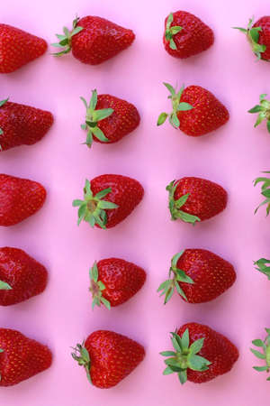 Fresh strawberries organized on pink background. Flat lay.