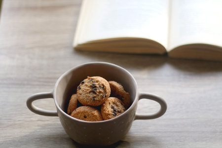 Bowl of chocolate chip cookies and open book on a table. Selective focus.の写真素材