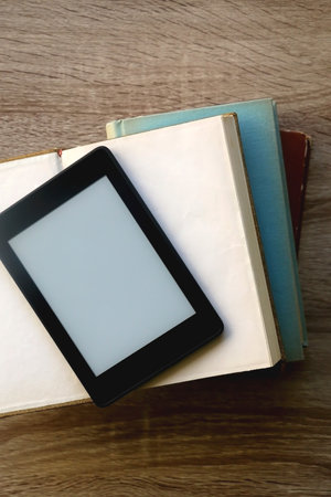 Stack of old hardcover books and e-reader on a table. Top view.の写真素材