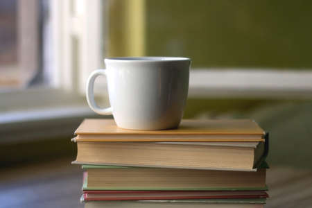 Stack of hardcover books and a cup of tea or coffee. Selective focus.の写真素材