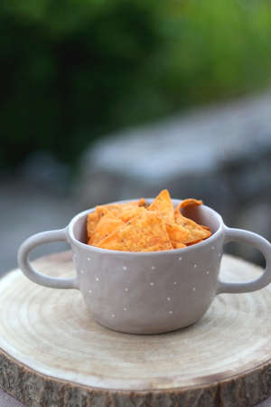 Bowl of spicy tortilla chips, served in a garden. Selective focus.
