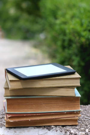 Stack of vintage hardcover books and e-reader on top. Selective focus.の写真素材