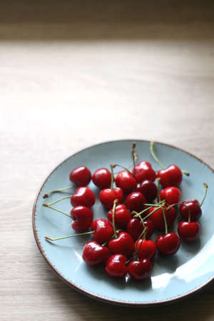 Blue plate filled with fresh cherries. Selective focus.の写真素材