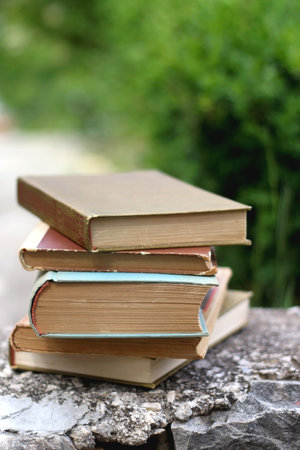 Split, Croatia - May 30, 2021: Stack of vintage hardcover books in a garden. Selective focus.のeditorial素材
