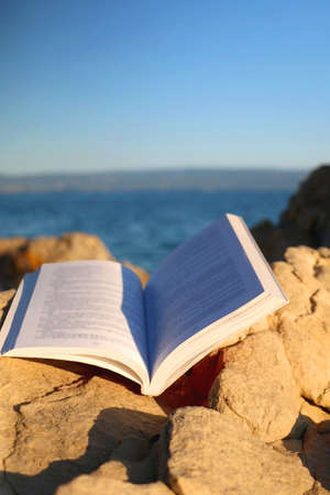 Open book on a beach, illuminated by sunlight. Selective focus.の写真素材