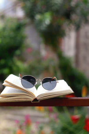 Open book and retro sunglasses in a garden. Selective focus.