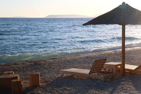 Bamboo parasol and wooden deck chair on a beautiful beach in Croatia.の写真素材