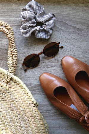 Straw bag, vintage shoes, sunglasses and scrunchie on wooden background. Flat lay.の写真素材