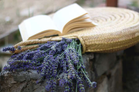 Straw bag filled with fresh lavender flowers and open book. Selective focus.の写真素材