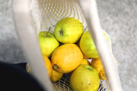 Crochet bag filled with apples and lemons. Top view, selective focus.