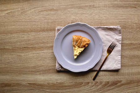 Slice of cheese and leek quiche on wooden table. Flat lay.