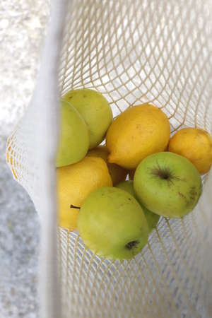 Crochet bag filled with apples and lemons. Top view, selective focus.の写真素材