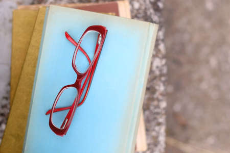 Stack of vintage books and reading glasses in a garden. Flat lay.の写真素材
