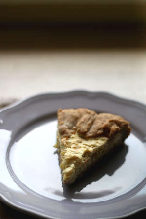 Slice of cheese and leek quiche on wooden table. Selective focus.の写真素材